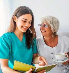 caregiver serving tea to a senior woman